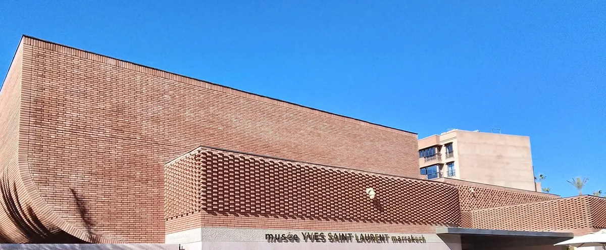 The red-brown brick facade of the Musée Yves Saint Laurent Marrakech, with its woven pattern of brickwork against a blue sky